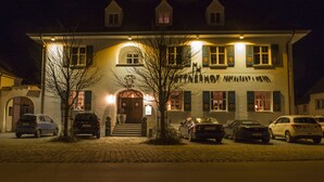 A two-story building with a central entrance, multiple windows, and a sign above the door. - Mettner Hof (Metten)