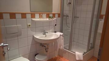 Un baño con lavamanos, espejo y ducha.