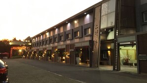 A modern building with multiple storefronts, a visible sign with Chinese characters, and a paved street in front. - Nikaido Bussiness Hotel (Minxiong)