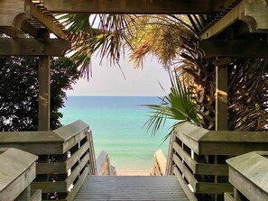 Un sentier en bois mène à une plage d’où l’on a une vue dégagée sur l’océan.