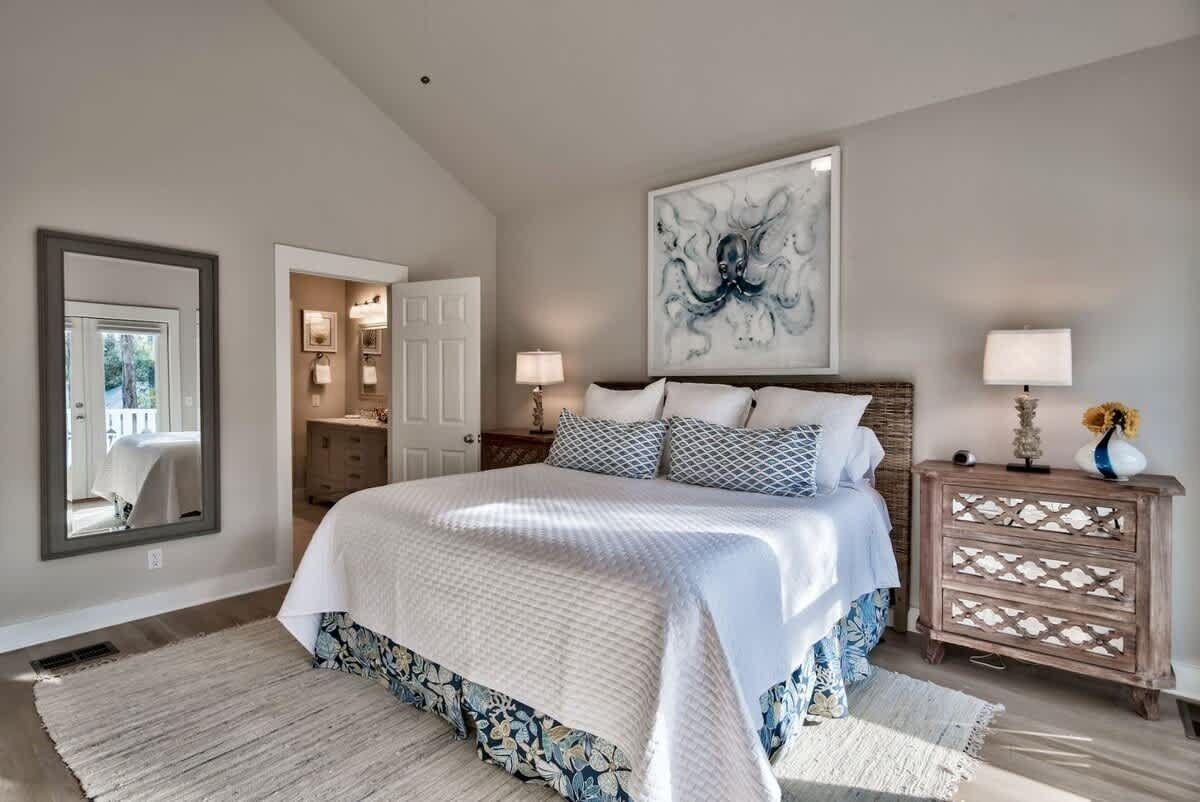 Un dormitorio con una cama grande, un aparador de madera, un espejo y una obra de arte en la pared.