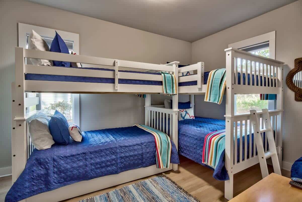 Een slaapkamer met stapelbed, een raam, een klein tafeltje en een stoel.
