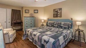 A bedroom with a bed, a chair, a dresser, a ceiling fan, and wall art.