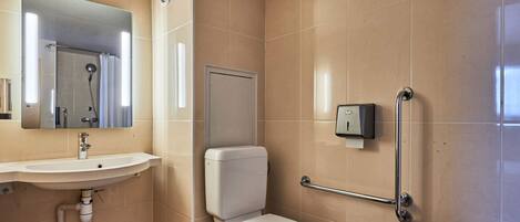 Un baño con lavamanos, inodoro y barras de apoyo.