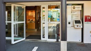 The entrance of a B&B hotel with a reception area, a self-service kiosk, and a sign indicating the hotel is fully booked.