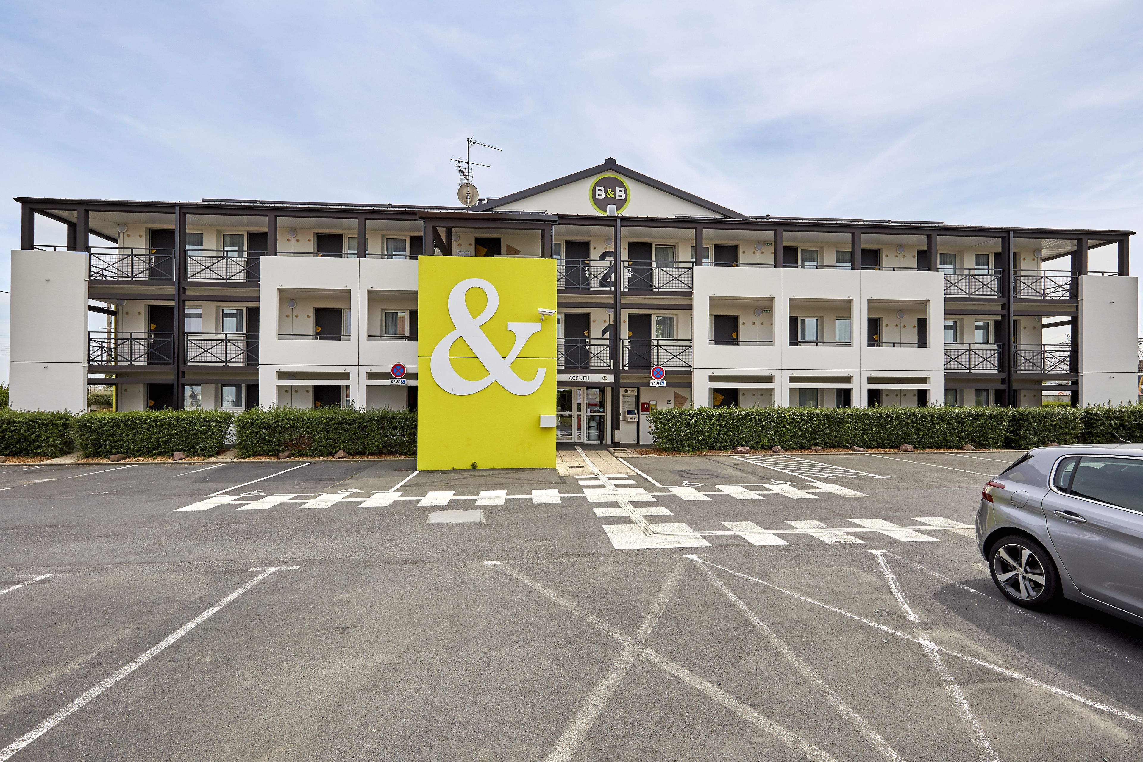 A multi-story hotel with a prominent yellow sign featuring a white ampersand symbol.