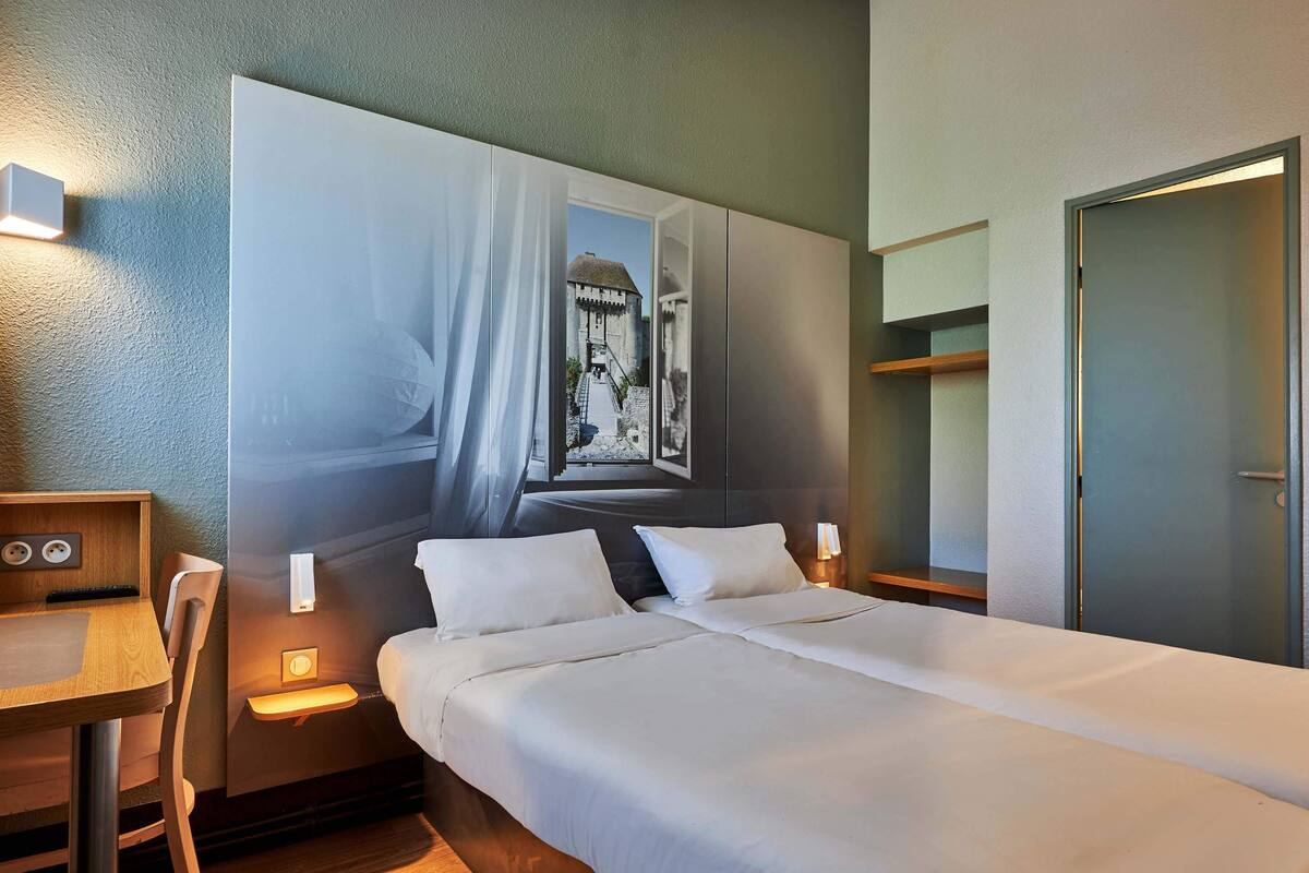 A hotel room with a large bed, bedside tables, a desk, and a wardrobe.