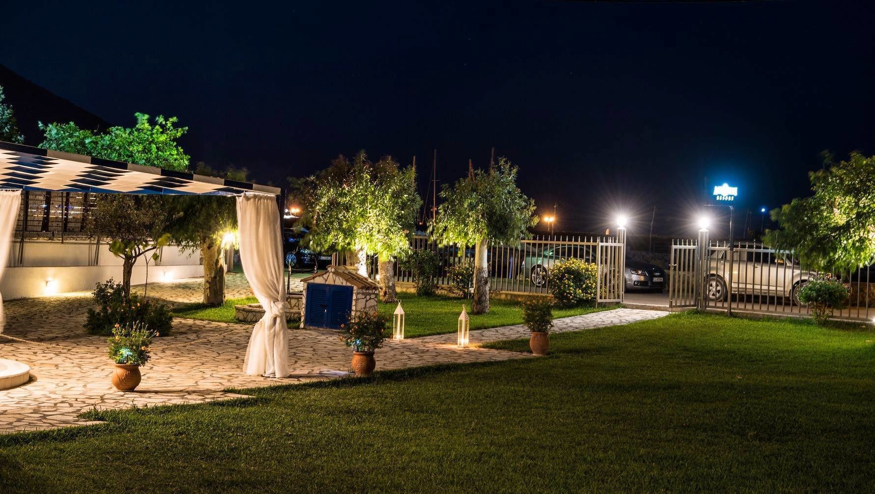 A well-lit outdoor area with a paved walkway, potted plants, and a small building with a blue door.