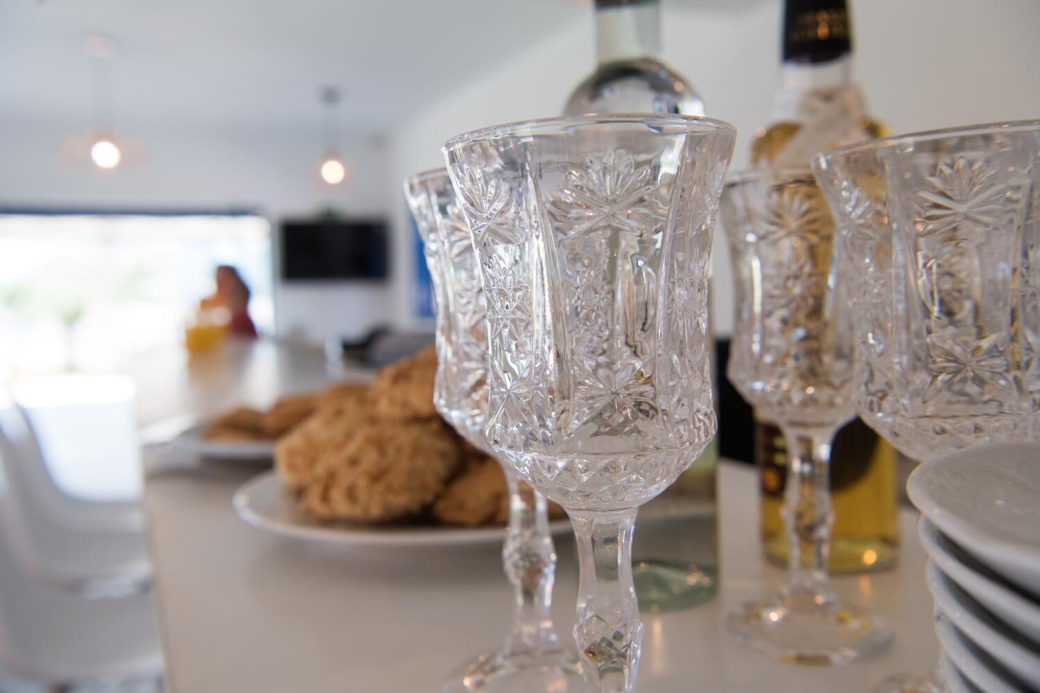 Een keuken met een wit aanrecht, een fles olijfolie en een bord koekjes.