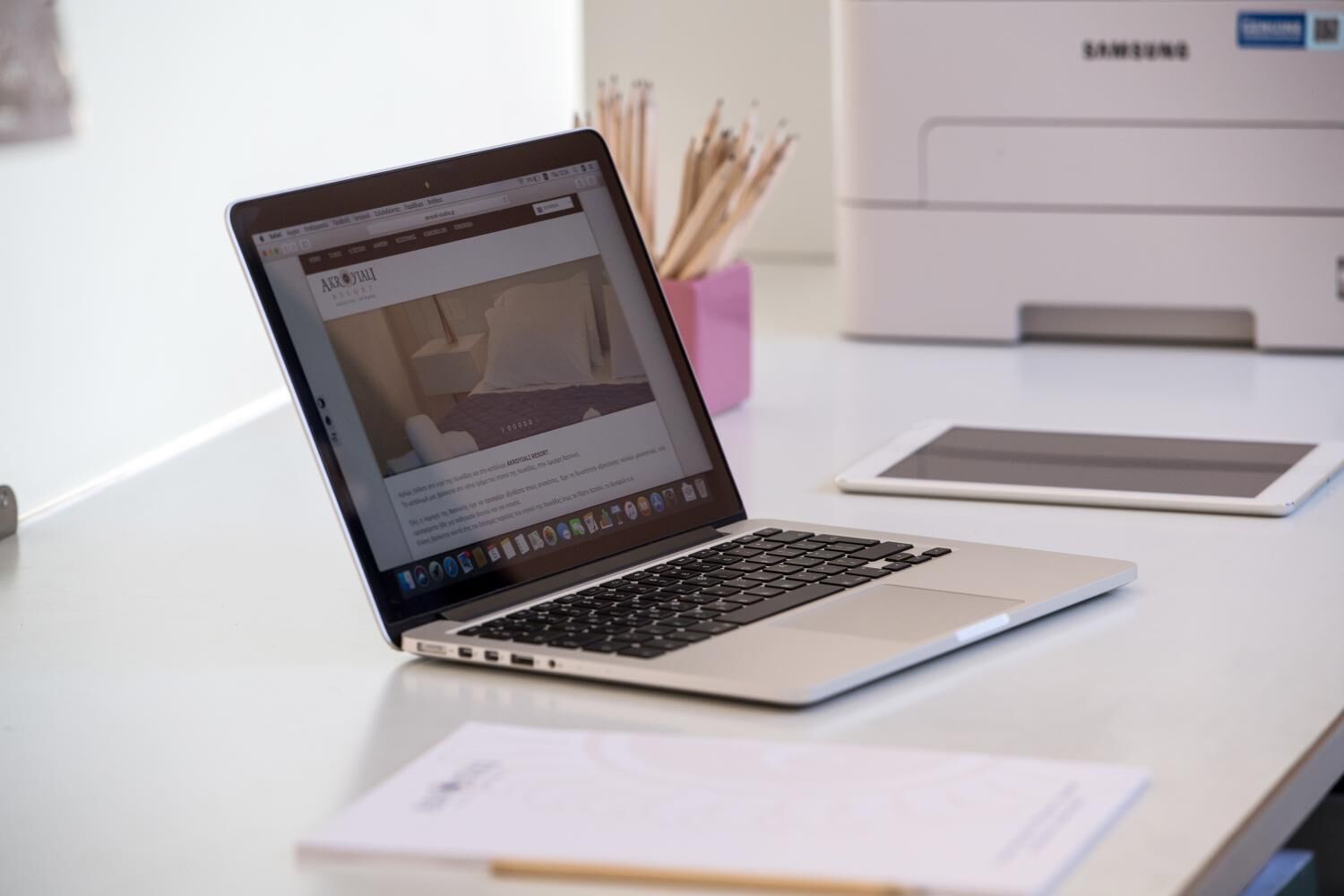 Un portatile su una scrivania, con una stampante Samsung sullo sfondo.