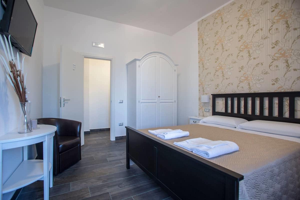 Habitación de hotel con cama, escritorio, silla, armario y televisor.