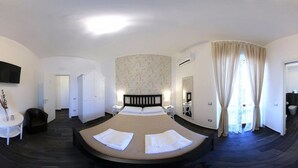 A bedroom with a large bed, a TV, a small table, a chair, a wardrobe, and a bathroom. - B&B Civico 41 Salerno (Salerno)