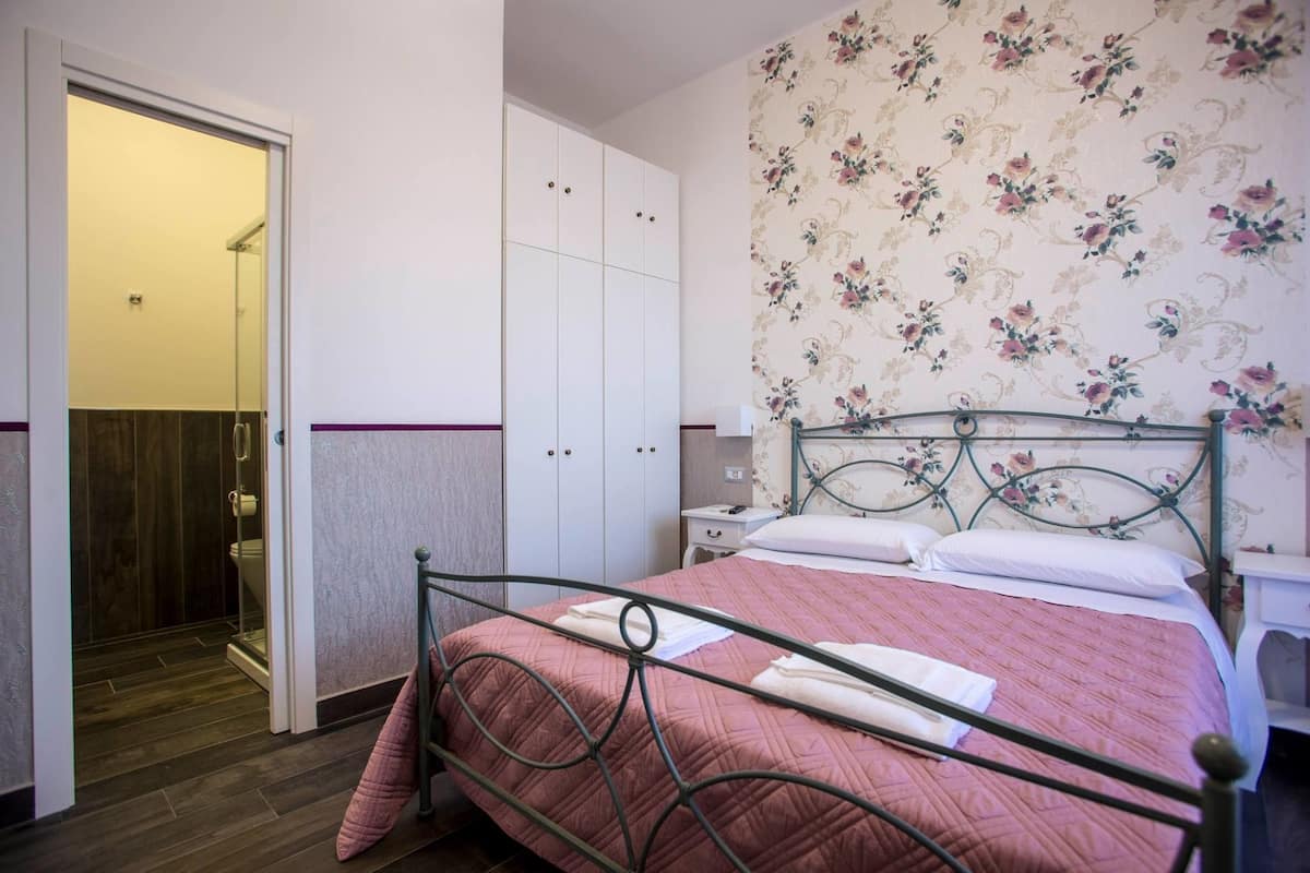 Un dormitorio con cama, armario y zona de ducha.