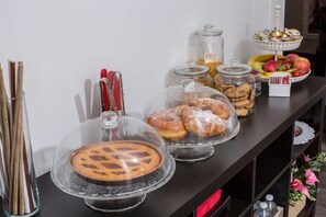 Ein Buffet mit verschiedenen Speisen, darunter Kuchen, Gebäck und Früchte.