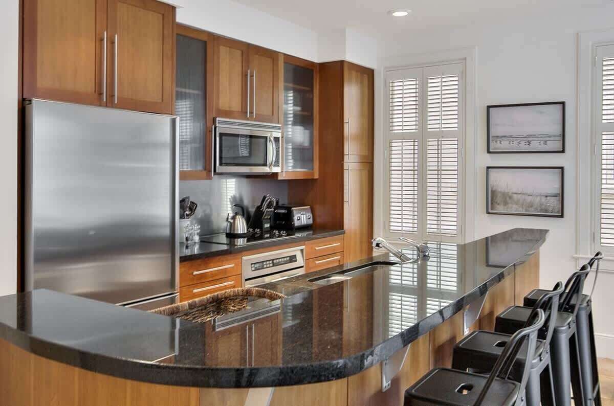 Una cocina moderna con electrodomésticos de acero inoxidable, armarios de madera y una encimera de granito curvada.