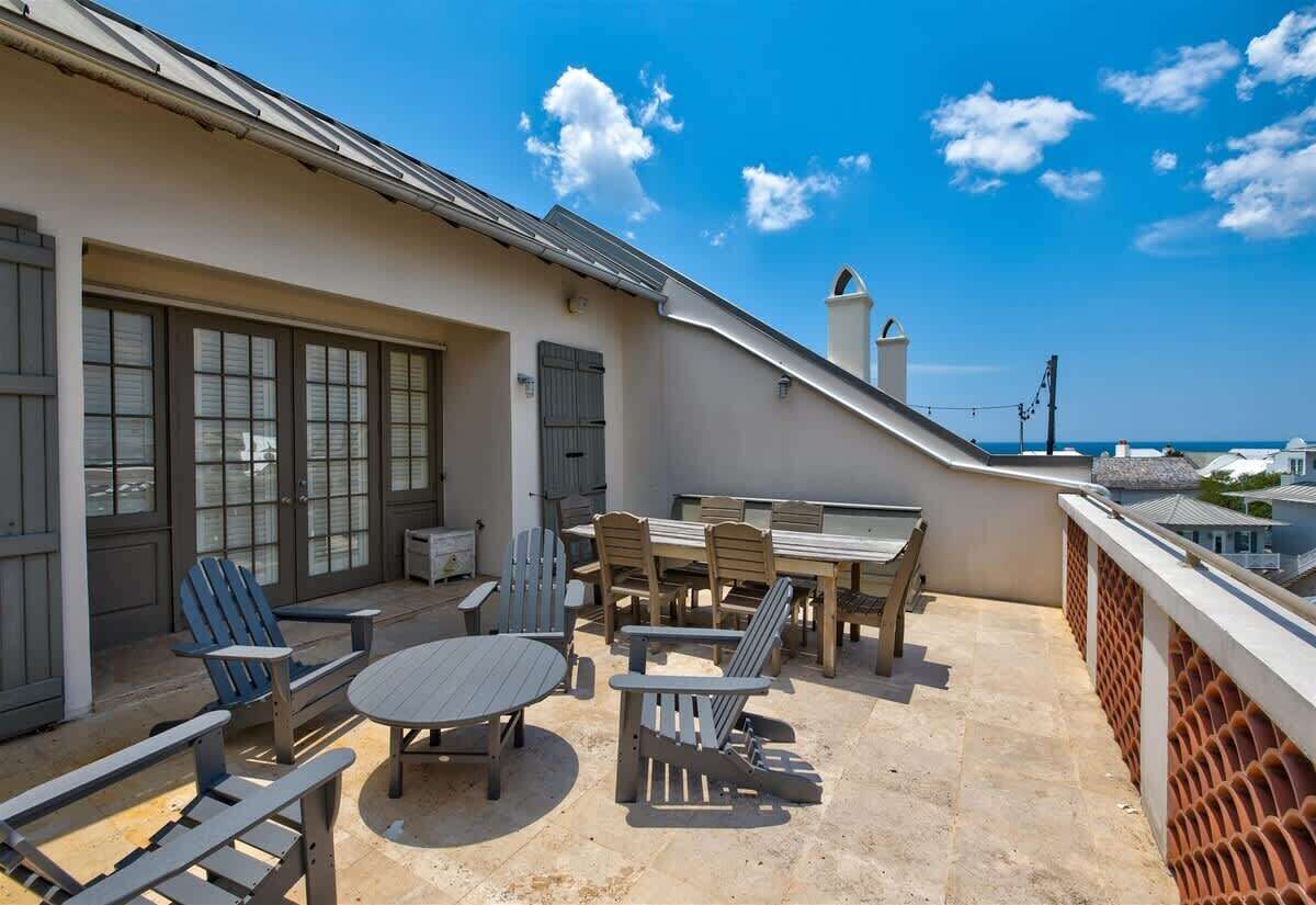 Una terraza en la azotea con una mesa de comedor, sillas y vistas al océano.