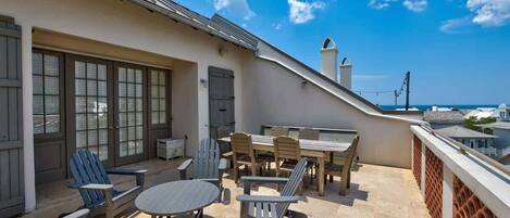 Una terraza en la azotea con una mesa de comedor, sillas y vistas al océano.