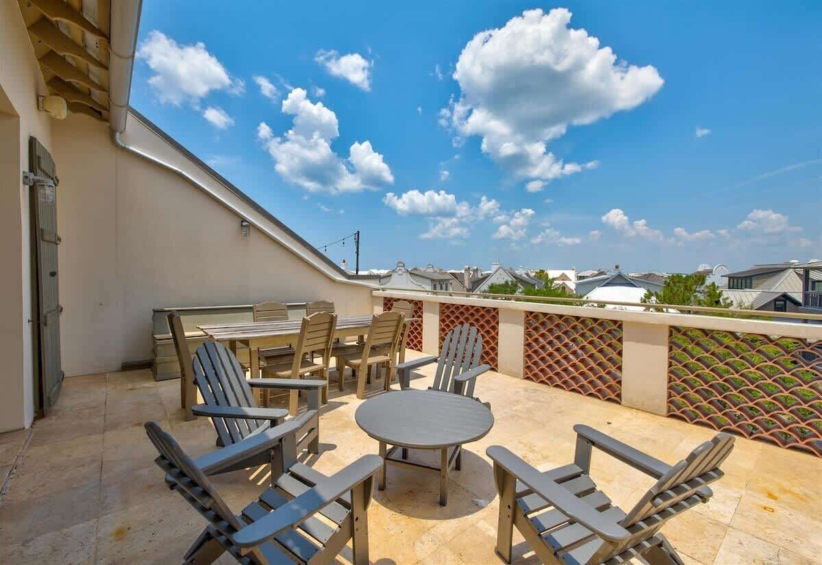 Una terraza en la azotea con mobiliario exterior, vistas del barrio y cielo despejado.