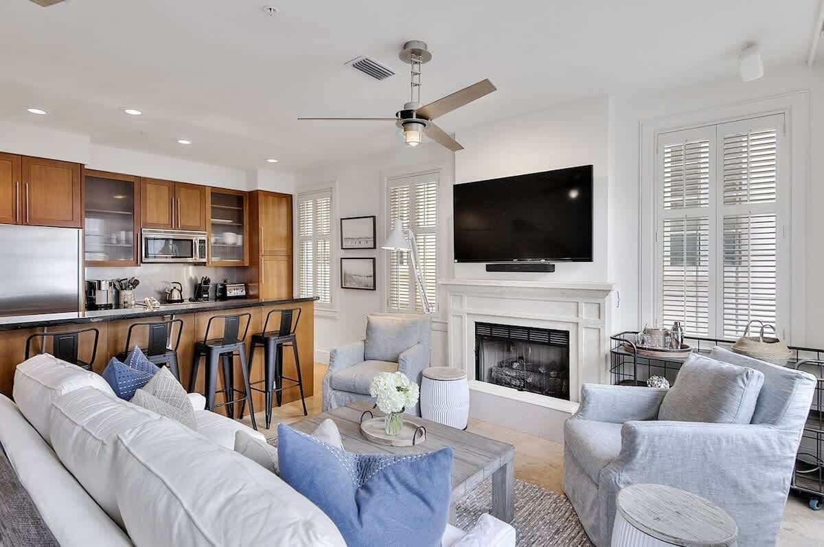 Una sala de estar moderna con sofá, sillones, una mesa de centro, chimenea, televisor y una zona de cocina con microondas.