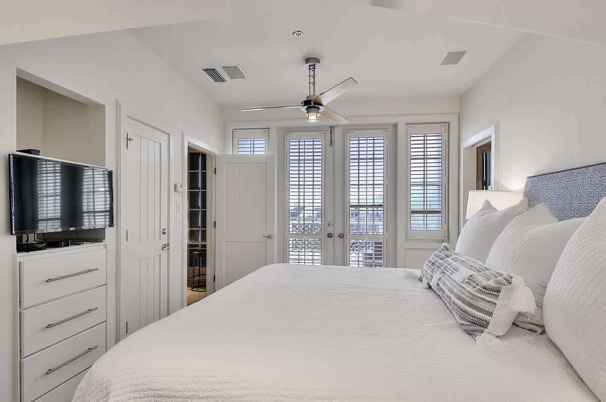 A bedroom with a bed, a ceiling fan, a TV, and a wardrobe.