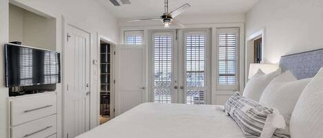 A bedroom with a bed, a ceiling fan, a TV, and a wardrobe.