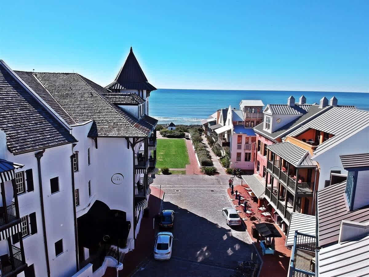 A coastal street with buildings, a clear sky, and the sea in the background.