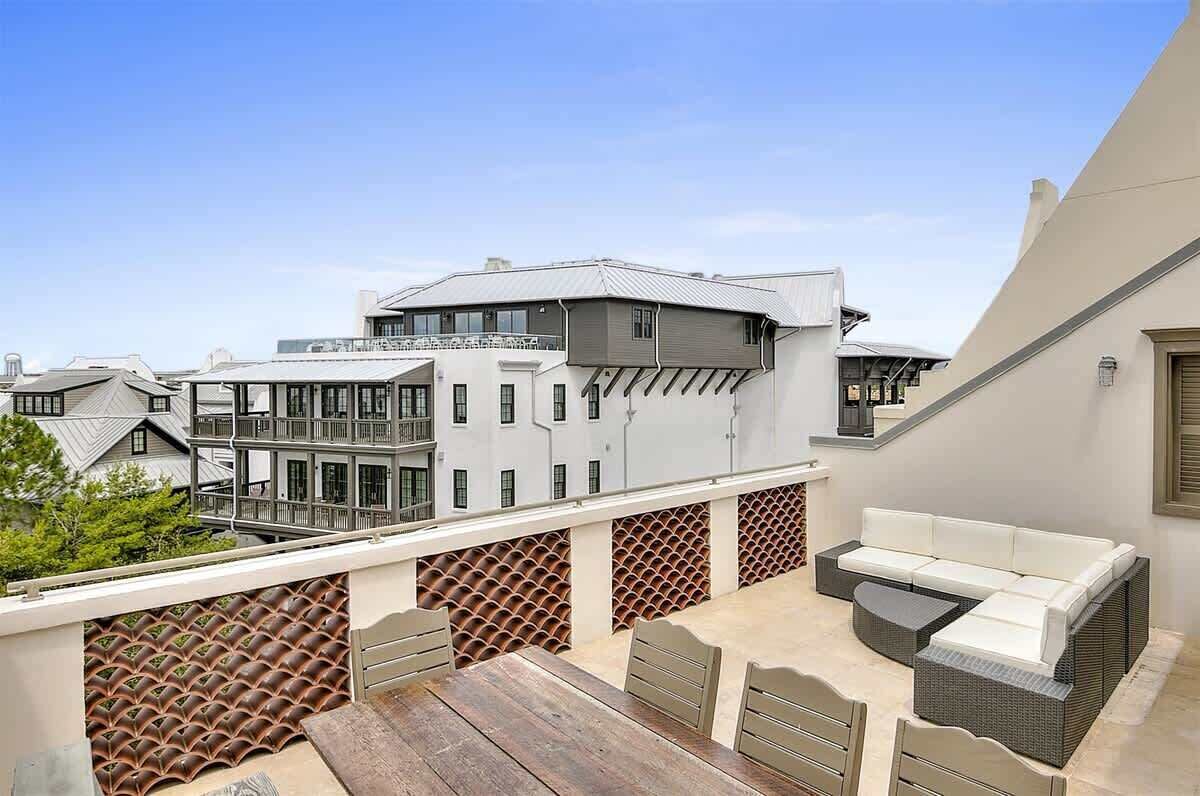 En tagterrasse med siddeplads, udsigt til omkringliggende bygninger og en mønstret væg.