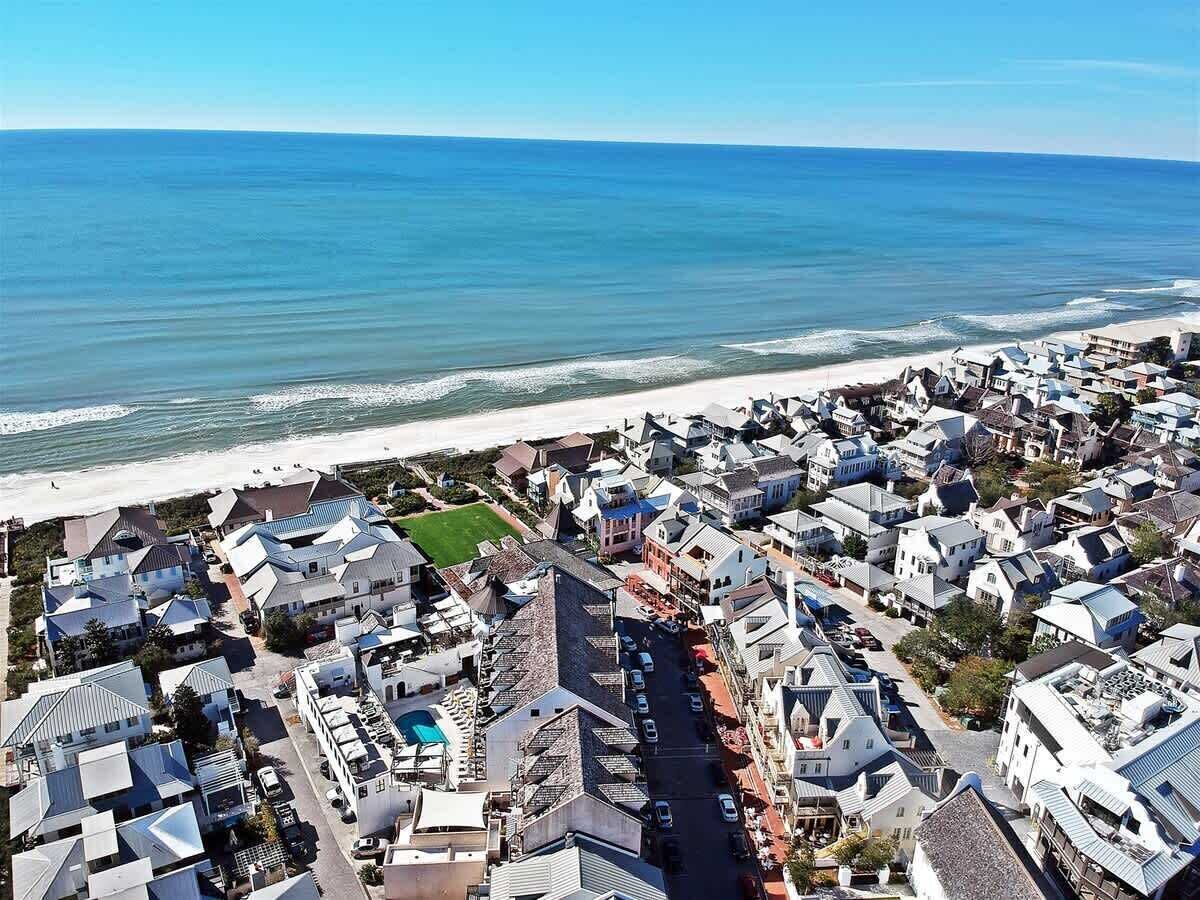 A coastal residential area with houses, a beach, and a clear sky.