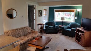 A living room with a sofa, two armchairs, a coffee table, a TV, and a lamp. - Lime Ridge Guest House  (Elkhart Lake)