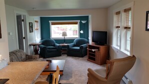 A living room with a sofa, two armchairs, a TV, and a dining table. - Lime Ridge Guest House  (Elkhart Lake)