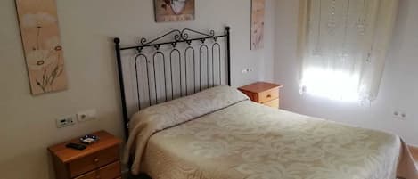 A bedroom with a bed, a nightstand, a dresser, and artwork on the walls.