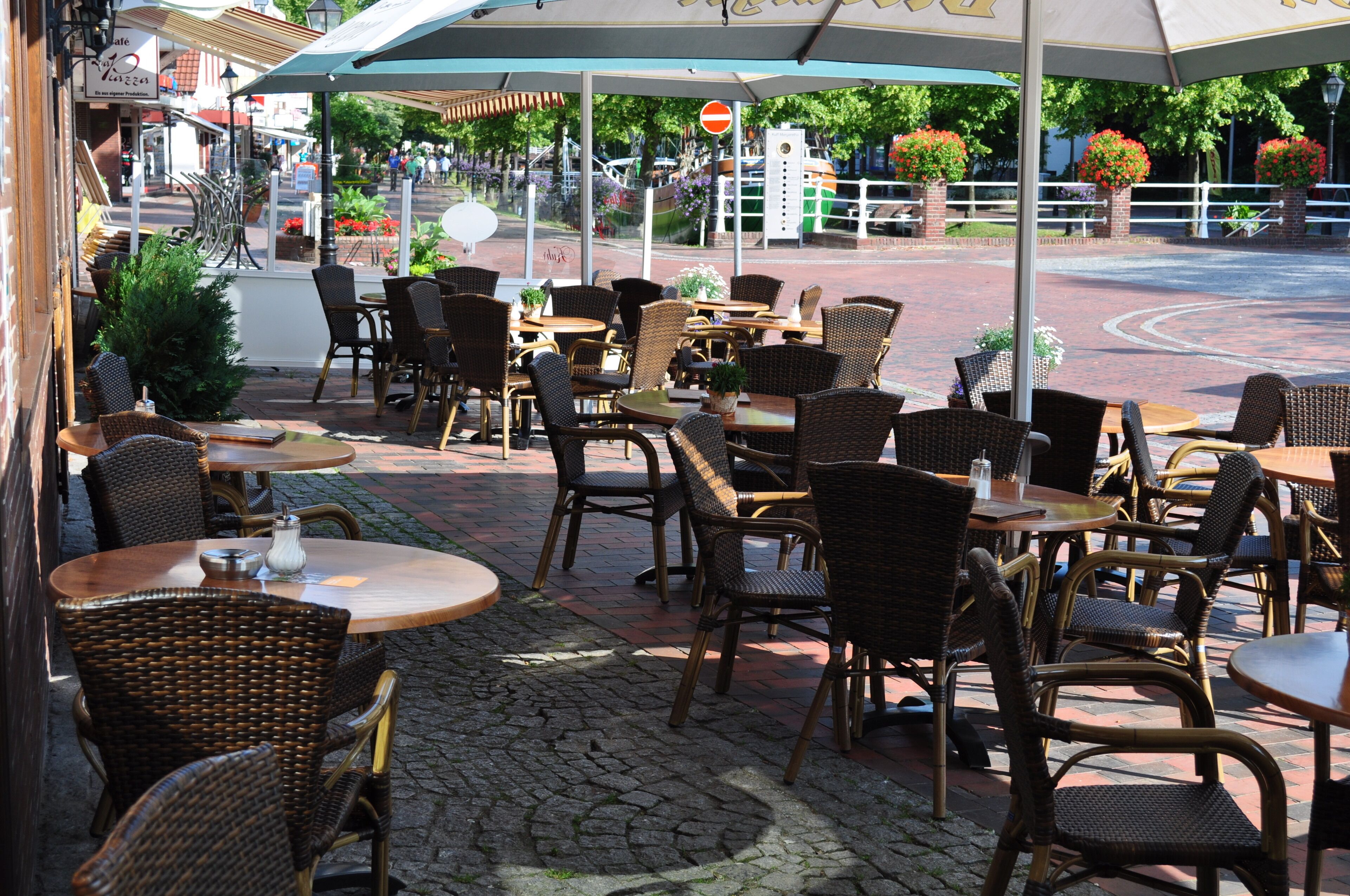 An outdoor cafe with wicker furniture and umbrellas.