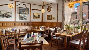 Restaurante com painéis de madeira, fotografias antigas e fachada de tijolos.