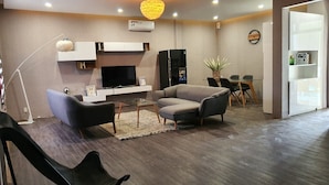 A modern living room with a flat-screen TV, a sofa, a coffee table, and a dining area with chairs. - Quy Nhon Hotel (Quy Nhon)