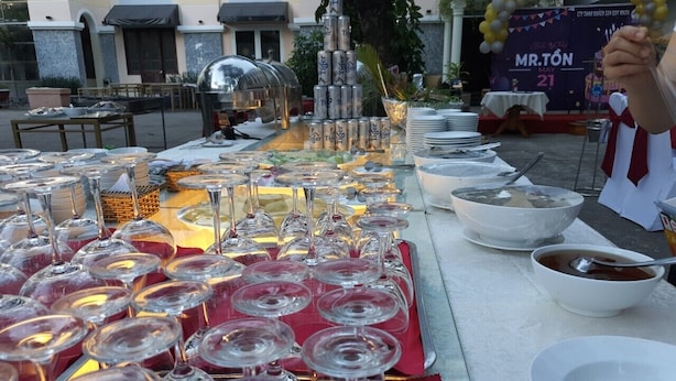 A buffet table with wine glasses, bowls, and a stack of cans. - Quy Nhon Hotel (Quy Nhon)