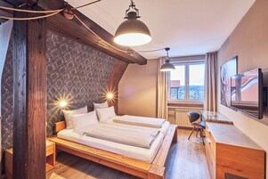 Quarto com cama de madeira, uma mesa de escritório e uma janela grande com vista.
