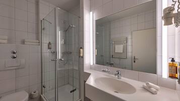 Une salle de bain moderne avec une douche à parois de verre, un grand miroir et un lavabo blanc.