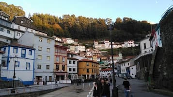 Un pueblo costero con edificios de colores, un paseo marítimo y un telón de fondo montañoso.