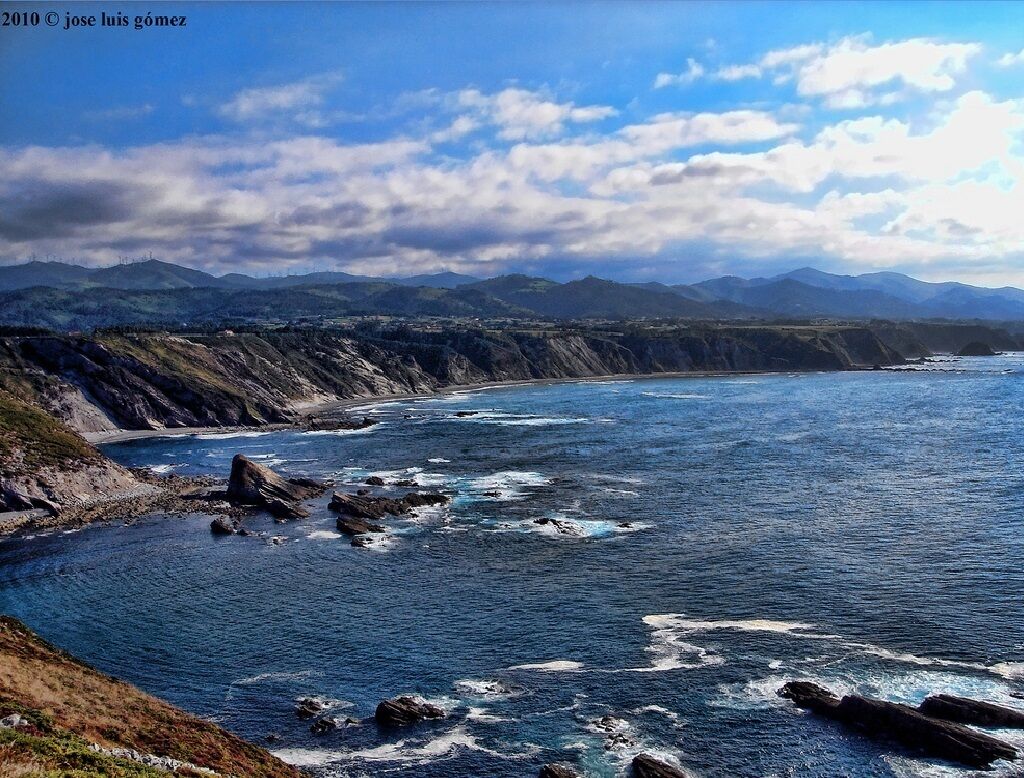 A coastal landscape with rocky cliffs and a clear view of the ocean.