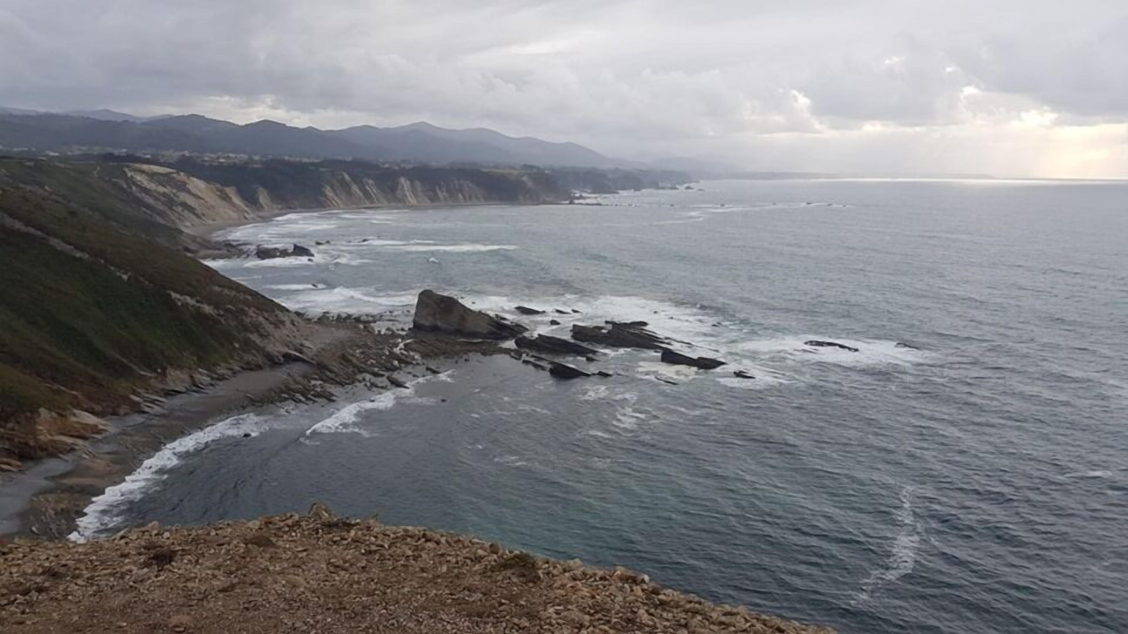 A coastal landscape with rocky cliffs and a view of the ocean.