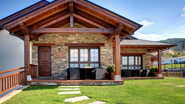 A stone building with a wooden porch, a door labeled "Corte de Slivov", and outdoor seating. - Apartamentos Rurales La Torre (Valdes)