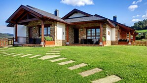 A two-story stone house with a wooden deck and a stone pathway leading to the entrance. - Apartamentos Rurales La Torre (Valdes)