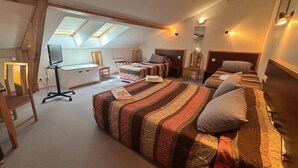 A bedroom with a large bed, a desk, and a chair. There are skylights above the bed. - Hôtel les Hirondelles (Orcines)