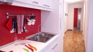 Une cuisine moderne avec des armoires blanches, un pare-feu rouge et un plancher en bois.