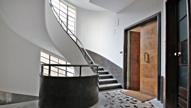 Un intérieur moderne avec un escalier en colimaçon, une colonne ronde et un sol à motifs.