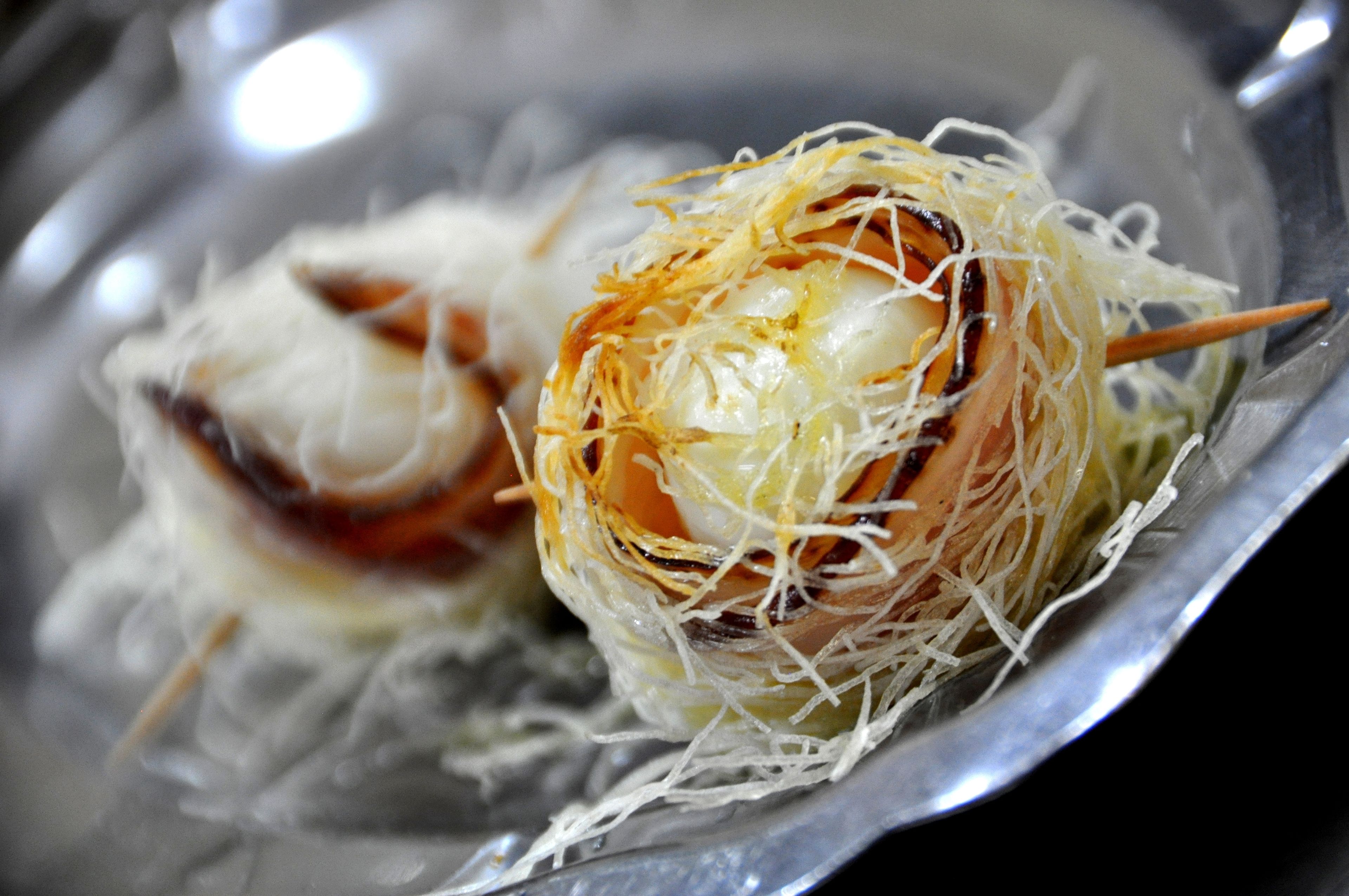 A close-up of a food item with a crispy outer layer and a soft interior, served on a metal plate.
