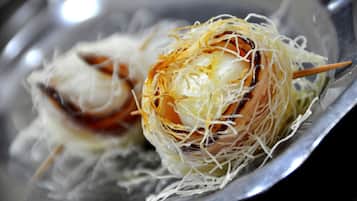 A close-up of a food item with a crispy outer layer and a soft interior, served on a metal plate.