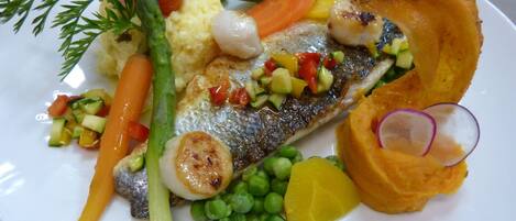 Un plato de comida con pescado, verduras y puré de papas.