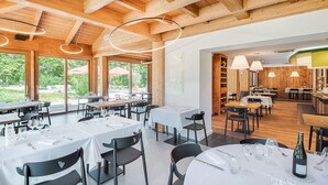 Een restaurant met houten balken, grote ramen en gedekte tafels.