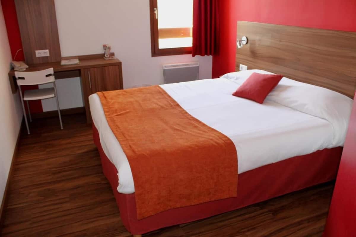 Een hotelkamer met een bed, een bureau en een stoel.